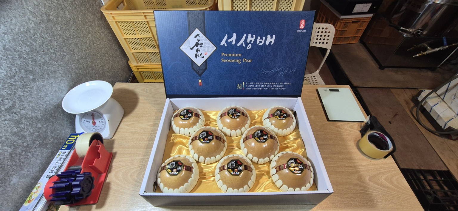 배순이네 과수원 작업대에서 개별 완충재와 금빛 속포장에 담은 신고배 여덟 알과 실제 프리미엄 선물 상자
